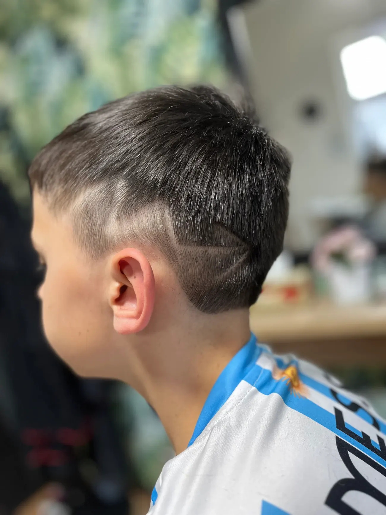 Vlasové tetování s vyholenými linkami v krátkém střihu, pohled z profilu