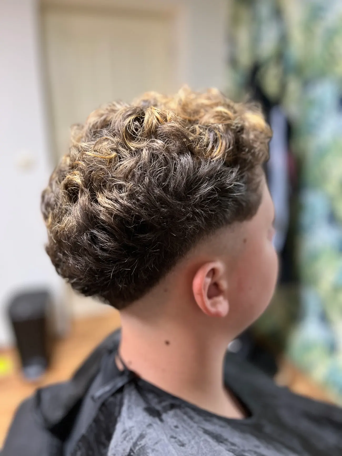 Curly Top Fade s kudrnatou horní částí vlasů a plynulým přechodem po stranách, pohled z profilu